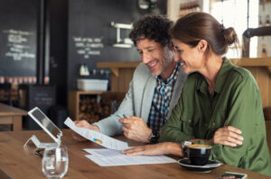 A middle aged couple discusses life insurance options at a coffee shop.