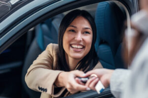 Car rental employee giving car keys to young woman.
