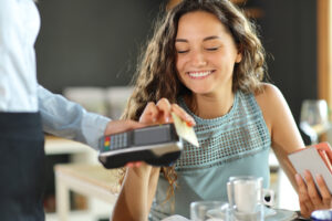 Smiling woman paying in a restaurant with credit card.