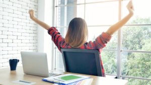 Relaxed woman turns away from computer and stretches, peaceful.