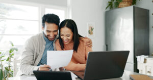 Cheerful couple examines credit score at the kitchen table together.