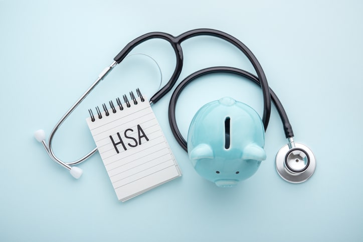 HSA wording on notebook with piggy bank and stethoscope. Guide to understanding HSA.