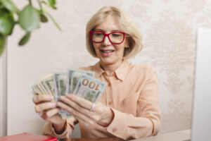 An older woman counts a pile of cash in her hands.