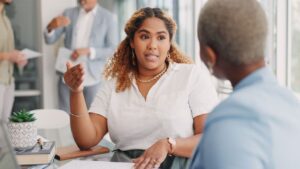 Woman in business attire sitting at a table and negotiating with another person.