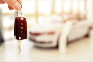 Car sales showroom and person holding car key in hands