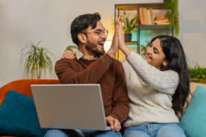 Happily surprised couple gives each other high-five after viewing online account.
