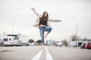 Ballerina dancing down the middle line of a road.