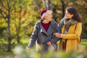 Granddaughter gets advice while walking and talking with grandmother in autumn.