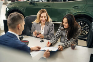 Young woman smiles while signing contract for the insurance of her new car.