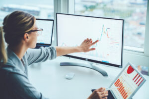Woman in glasses studying financial markets on a computer screen, to calculate possible risks and profits.