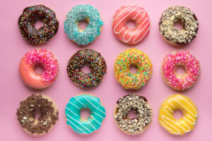 Colorful glazed donuts on pink background.