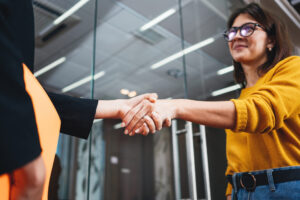 Women in a bank shake hands after discussing a loan.
