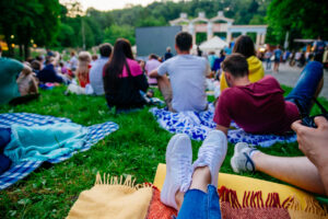 People watching movie in open air cinema in city park.