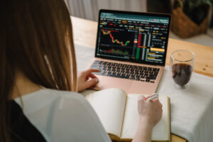 View over a woman's shoulder of her laptop screen showing an investing graph.