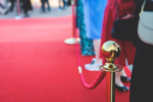 Red carpet with ropes and golden barriers at a luxury party entrance.