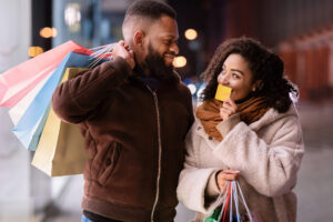 Smiling woman holds credit card and looks at husband after shopping with him.