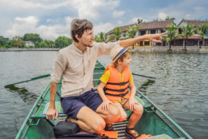 Dad and son tourists in boat on the lake Tam Coc, Ninh Binh, Viet nam.