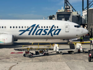 Alaska Airlines plane parked at the gate with luggage cart