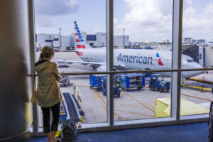 Close-up view of woman talking on mobile phone at the airport with American Airlines plane in the background