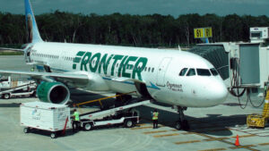 Frontier Airlines plane parked at the gate with the luggage ramp out and ground crew
