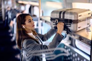 Woman putting her bag on luggage rack while traveling by train.