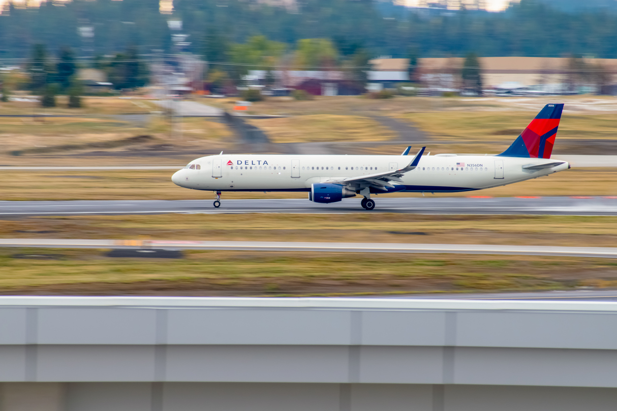 A Delta airplane landing on the runway during the day