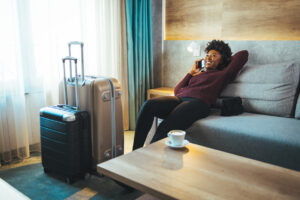 A woman relaxes on a couch with her suitcases, chatting on the phone during her layover.