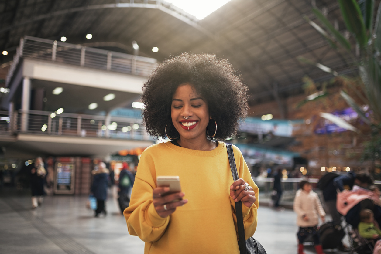 Smiling woman using smartphone in airport terminal