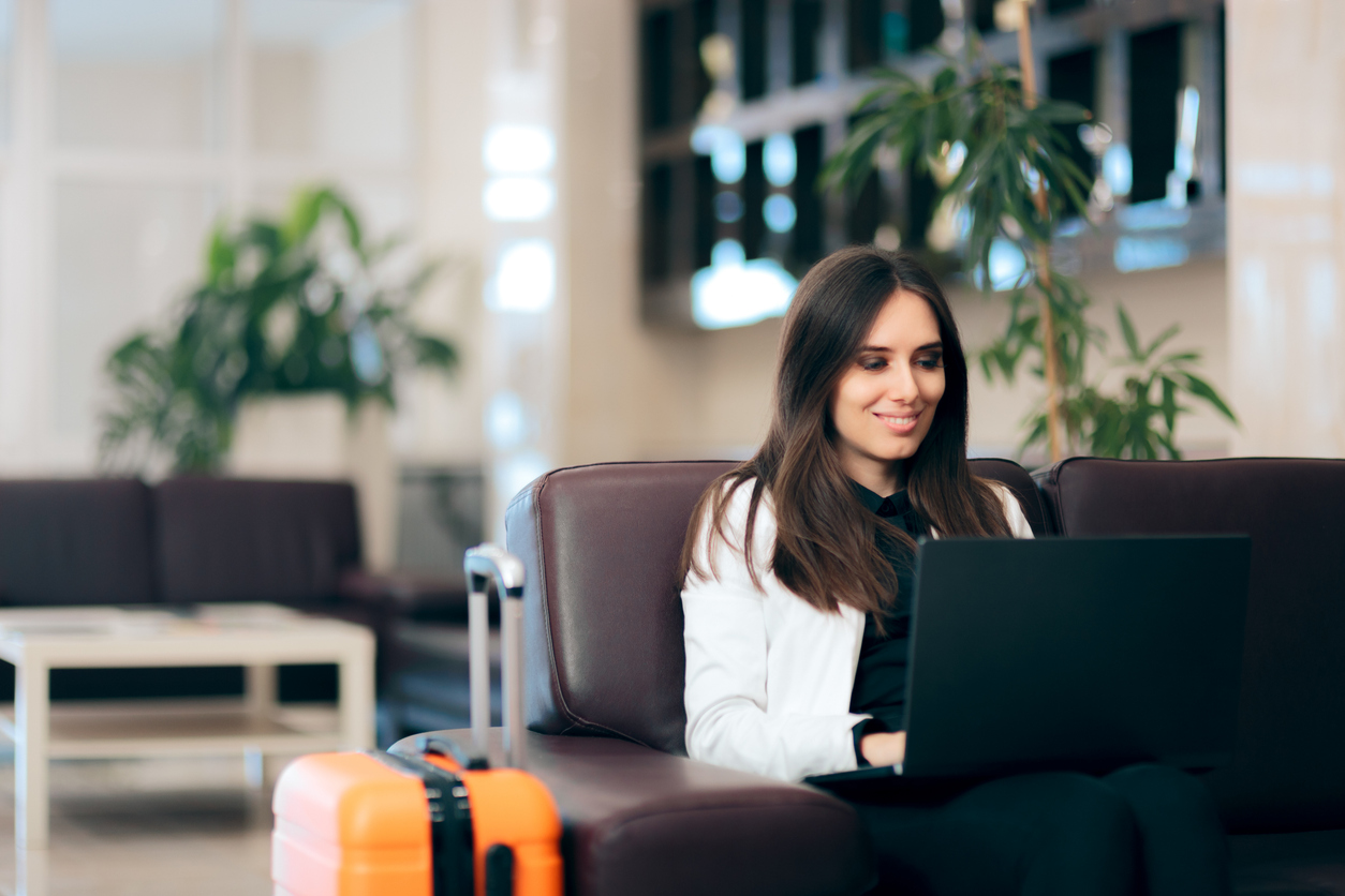 Woman with laptop and luggage sitting in an airport lounge