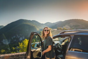 Young woman getting out of her car in the mountains on a summer vacation