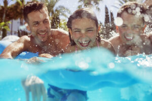 Father swimming with his two children in swimming pool.
