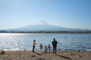 A family stands in front of Mount Fuji at Lake Kawaguchiko in Yamanashi Prefecture in Japan.