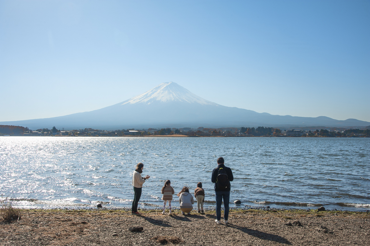 A family stands in front of Mount Fuji at Lake Kawaguchiko in Yamanashi Prefecture in Japan.