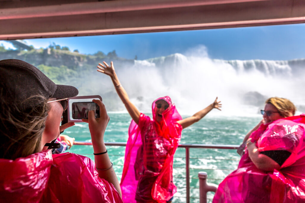 A group of tourists having fun using red raincoats inside a boat close to the falls in Niagara Falls Canada