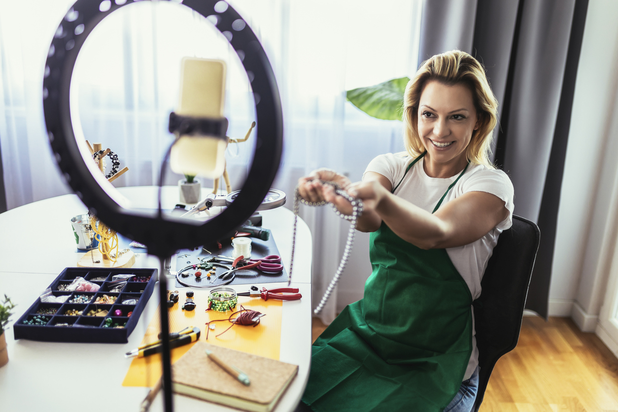 Woman filming herself showing her handmade jewelry