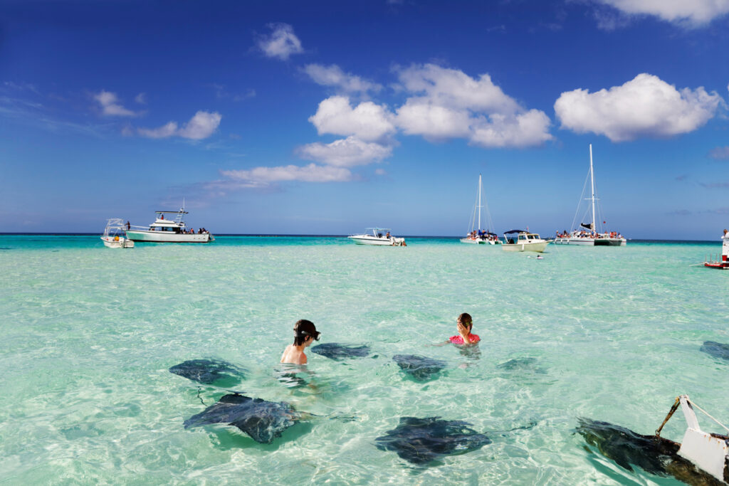 Kids snorkeling in clear ocean with stingrays