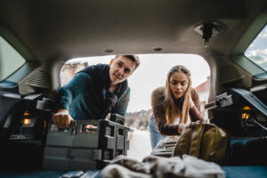 Interior view of man and woman loading baggage and belongings into the back of a car.