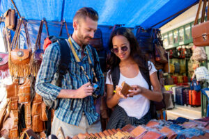 - Erika Kullberg Two tourists looking at leather products in a shopping stall.